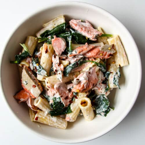 Salmon & spinach pasta in a white bowl.