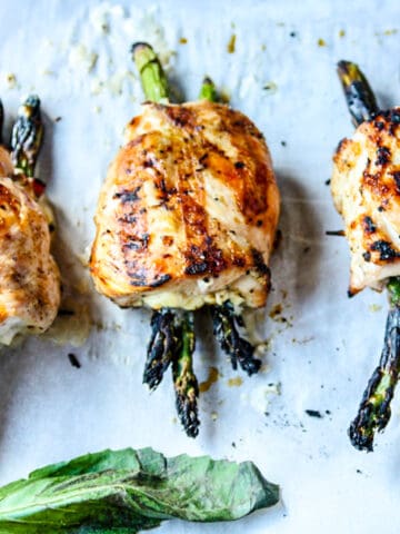 Three grilled asparagus stuffed chicken breasts on a tray.