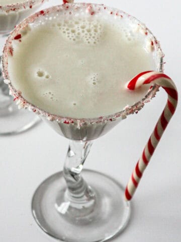 Candy cane martini in a martini glass, garnished with a candy cane.
